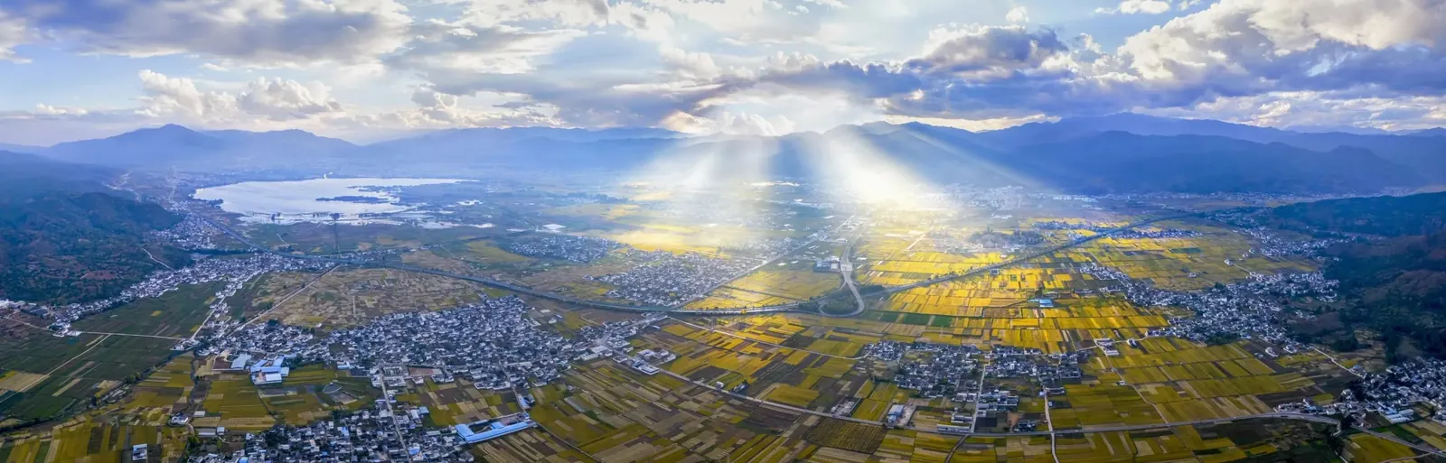 Aerial dawn view from the Cangshan Mountains over golden fields and a sea of cloud