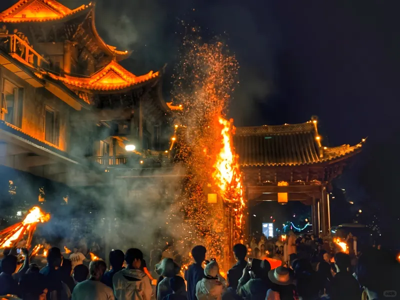 A towering torch showering sparks on the night of the Torch Festival