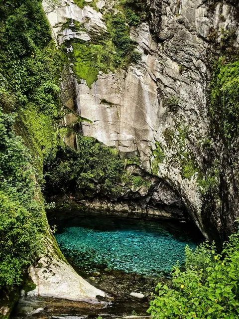 A clear green pool beneath cliffs on Cangshan