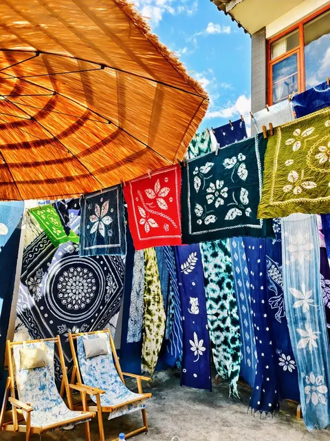 Tie-dye fabrics and a straw umbrella in a Zhoucheng workshop